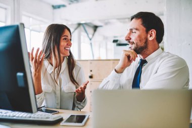 Düşünceli erkek yaş dikkatlice dinleme çekici gülümseyen kadın iş arkadaşı sırasında işbirliği modern ofis içinde sakallı. İyi bir atmosferde iletişim olumlu erkek ve kadın grafik tasarımcıları
