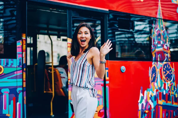 Portrait of excited young asian woman getting in sightseeing bus enjoying visiting city landmarks, surprised female traveler happy about having excursion and city tour in Moscow looking at camera