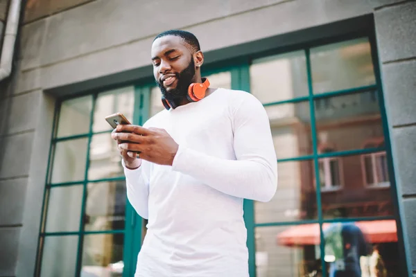 Pozytywne Afro Amerykański Facet Słuchawkami Wyszukiwanie Ulubionych Piosenek Pobrania Mobilnych — Zdjęcie stockowe