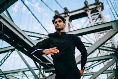 Profesyonel erkek koşucu etkin giymek için sağlıklı canlılık ve fiziksel gücü kentsel ortamda hızlı çalışan iş için giyinmiş. Köprüde sabah eşofman eğitimdeki motive sporcu