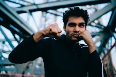 Motive genç spor formu ve canlılık korumak için kentsel ortamda boks eşofman giymiş adam yerleştirmek. Elele yüz yakın ve sıcak sırasında egzersizleri yaparken etkin aşınmaya ciddi sporcu