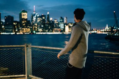 Sporcu arkadan görünüm akşam şehir sahne ayakta açık havada Nehri yakınında zevk gri eşofman giymiş. Etkin aşınmaya kentsel bir ortamda yürüyüş kasaba durig gecesi arıyorum erkek koşucu