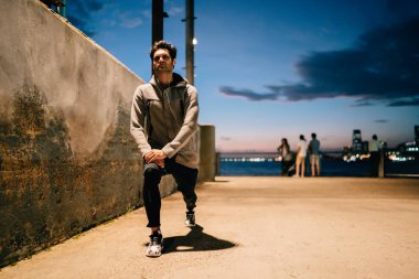 Gri eşofman bacaklar yukarı kentsel ayarlarında çalıştığını akşam önce ısınma motive erkek atlet. Jogging yapan modern şehir açık havada sporda meşgul. Alacakaranlık olarak çalışma sırasında aktif giyim giymiş sporcu