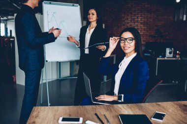 Meslektaşları süre kamera flip grafik yakınındaki fikirler tartışmaya zemin üzerine bakarak işkadını gülümseyerek oturan ofis dizüstü bilgisayar ile çalışma işlemi sırasında müreffeh kadın Yöneticisi portresi