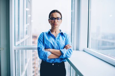 Kendine güvenen deneyimli iş kadını ile yarım uzunluk portre ofis, ciddi kadın gurur CEO'su resmi kıyafeti ve kameraya bakarak gözlük giymiş coworking ayakta silah geçti