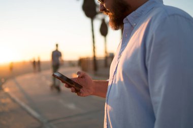 Genç adam erkek hipster smartphone holding modern uygulama Tebliği kontrol sokak, kırpılmış görünümü üzerinde duran cep telefonu 4 g bağlantısı kullanma sosyal ağlardan video izliyor sakallı