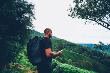 Uzun yürüyüşe çıkan kimse ile seyahat etmek sırt çantası ve mobil yönlendirmek el manzara güzel sahne zevk deneyimli erkek sakallı ve dağlar yaz aylarında yeşil saç ekimi ile Asya konumda trek