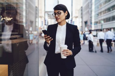 Metropolis'te geziniyor ve telefona para transfer formal giyim kendine güvenen kadın avukat. Ciddi sahibi iş bölgesi üzerinde yürüme ve Smartphone'da mesajlaşma paket servisi olan restoran kahve fincanı holding
