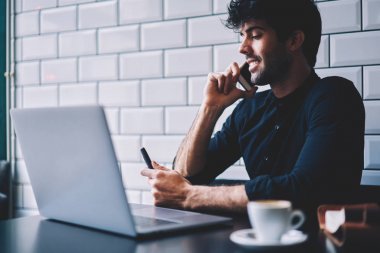 Neşeli işadamı smartphone aygıtında mesafe işi sırasında dijital netbook konuşurken şık gömlek giymiş. Dizüstü bilgisayar başında oturan cep telefonunda iletişim olumlu erkek Yöneticisi
