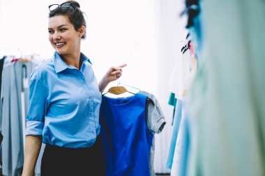 Yetenekli genç tasarımcı giyim yeni gelecek koleksiyonu ayakta için kendi showroom seçme. Askıları trendy giyim ile elinde tutan ve kıyafet daha iyi türevi düşünme başarılı terzi