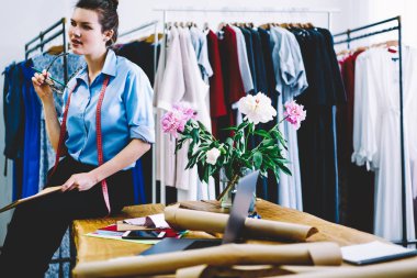 Gözlük ve boyun düşünme üzerinde fikirler trendy giyim masaüstünde arka plan üzerinde şık elbiseler ve aygıtlar ile oturan yeni koleksiyonunun kasette ile profesyonel stilist durulması