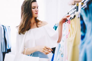 Çekici şık giyimli kadın moda deposunda giysiler seçmek alışveriş için kararı konsantre. Şık güzel erkek giyim showroom trendy bir görünüm oluşturmak için yetenekli tasarımcı aranıyor