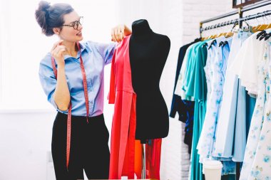 Dikkatli bir şekilde yeni koleksiyonu şık giyim kendi showroom çalışma tasarımını geliştirmek için fikirleri üzerinde düşünürken pembe Tekstil malzeme ile siyah manken seyir yaratıcı kadın modacı