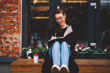 Muhteşem yaratıcı kadın blogger not defteri komik fikirler için kişisel web sitesi yayın yazma şık giyim giymiş. Gülümseyen yetenekli öğrenci dışında yaklaşan muayene için hazırlanıyor