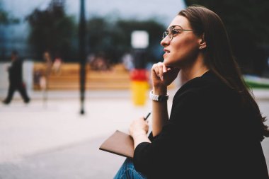 Boş vakit Street ve çalışma programı planlama daha iyi görüş için serin gözlük genç sevimli esmer kadın. Uzakta, otururken sokak ve düşünme seyir tatlı hippi kız