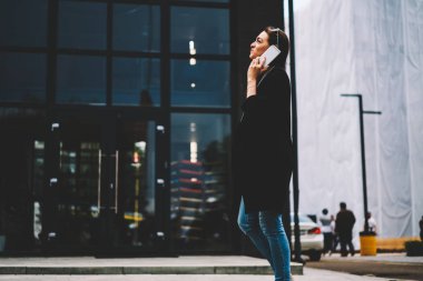 Genç pozitif kadın ile sokulgan yolu ile uygulama için 4 g bağlı smartphone cep telefonu ile şık moda giyim iletişim içinde giyinmiş. Sokağı'nda yürüyüş ve telefonla konuşurken mutlu genç