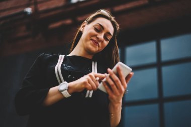 Çekici olumlu kız öğrenci smartphone cep telefonu ile Web sitesi ilginç video izlerken rahat kıyafetler giymiş. Mutlu hippi kız cep uygulaması ile arkadaş komik iletiler göndermesi