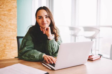 Yarım uzunluk portre çekici yaratıcı öğrenci modern dizüstü bilgisayar başında oturan kamera gülümseyen bağlı 4g internet. Dijital netbook ofis iç çalışma neşeli kadın serbest meslek