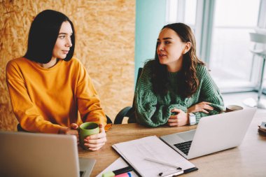 İki öğrenci rahat kıyafet Üniversitesi'nde kahve molası sırasında birbirleriyle iletişim kurmak giymiş. Kadın grafik tasarımcıları, modern dizüstü bilgisayarlar ofisinde otururken iç konuşuyor