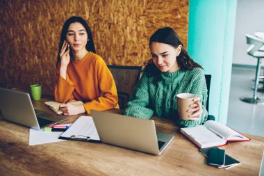 Ofis iç oturma dizüstü bilgisayar aygıtları, çalışan iki kadın grafik tasarımcıları. Kadın Yöneticisi internet'e bağlı bilgisayarlardaki yeni görevdeki meslektaşım ile işbirliği süre Smartphone'da konuşuyor