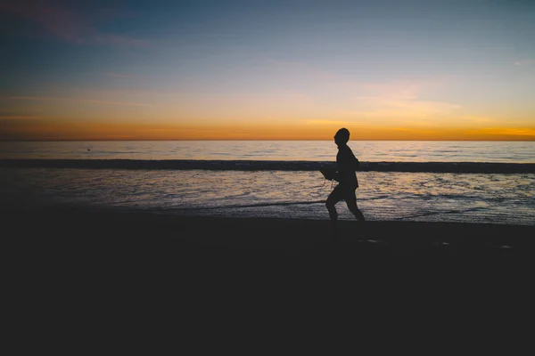 男性剪影的慢跑开始一天清晨的活动在海洋海岸线上 男子在沙滩上运行黄昏暮光和日落花在热带 Islan 的暑假 — 图库照片