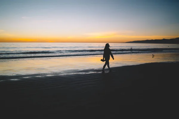 女人的身影漫步在沙滩上 美丽的金色日落 在平静的水面上 孤独的女孩漫步在海边的海岸线上 望着风景明媚的黎明在夏日重现 Vacatio — 图库照片