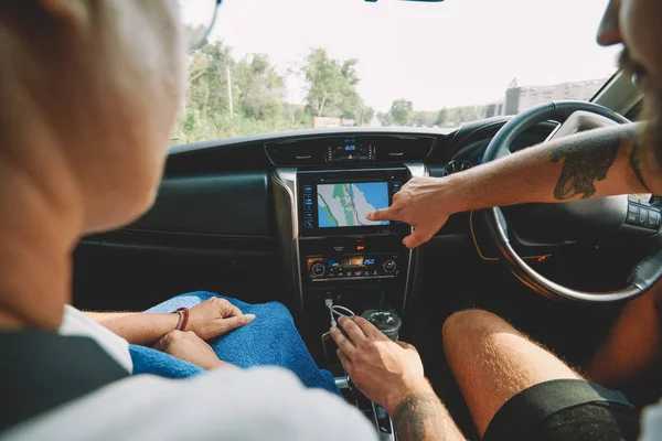 夏の旅行中に実権を握って座っているレンタカーの現代オンライン ナビゲーターの表示に正しい方向を指す つの観光客のトリミング画像です 車のダッシュ ボード上のルートを選択する様に — ストック写真