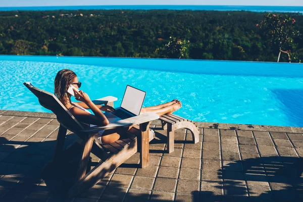 年轻性感的女人在太阳镜上谈论智能手机 而做远程工作在笔记本电脑与空白复制空间屏幕区域的信息内容使用良好的无线互联网在暑假期间 — 图库照片