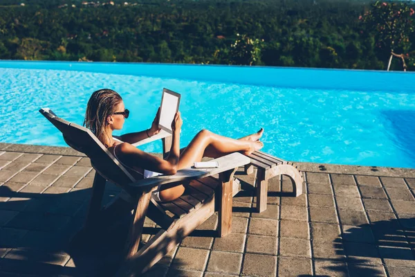 年轻有魅力的妇女在太阳镜阅读新闻网站上的现代触摸板设备与空白屏幕区域连接到4G 互联网 而休息在日光浴和享受夏季在假期 — 图库照片