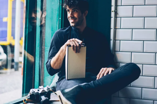 Uśmiechający Się Młody Człowiek Ubrany Czarną Koszulę Patrząc Okna Trzyma — Zdjęcie stockowe