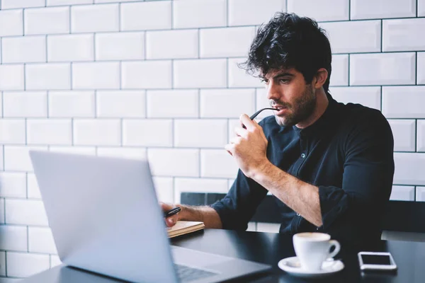 专注的男性平面设计师在笔记本电脑上仔细观看在线课程 连接到4G 互联网 对咖啡店上网本工作的沉思企业家核算数据库 — 图库照片