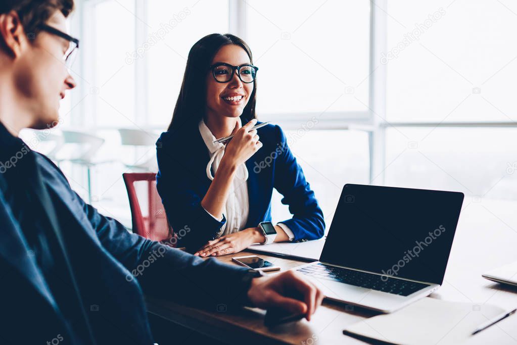 Cheerful female assistant of male executive manager satisfied with ocupation developing strategy with boss,colleagues collaborating during meeting table enjoying friendly atmosphere an discussion