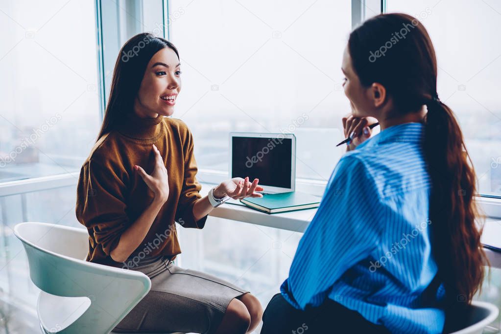Surprised female share information with colleague during working day in office discussing success in business project,emotional woman speaking about conmany good news sitting with friend coworker