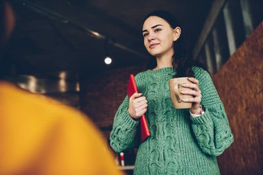 Büyüleyici kadın Müdürü lezzetli içecek ve eller klasöründe holding esmer saçlı. Yaratıcı tasarımcı giyim ayakta çay bir fincan ile oda ofis giyinmiş