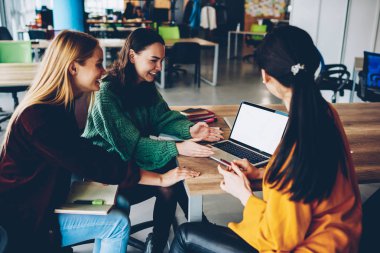 Öğretici birlikte kablosuz internet kullanarak verimli işbirliği için izlerken mutlu yetenekli öğrenciler dizüstü bilgisayar boş ekran ile bağlı. Sunum üzerinde olumlu tasarımcıları teamworking