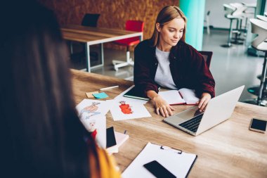 Yüksek olarak bağlı dizüstü bilgisayar, grafik geliştirme yaratıcı bonde tasarımcı çalışma hızda internet. Genç kadın masaüstü netbook ve çizimler ile oturan web sitelerinde yeni fikirler arıyor