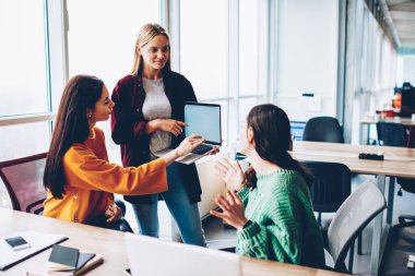 Arama bilgi için dizüstü bilgisayar ve internet kaynakları kullanarak tasarım proje üzerinde üç yetenekli öğrenciler teamworking. Office Çevrimiçi sunu üzerinde birlikte yaratıcı moda çalışanlar