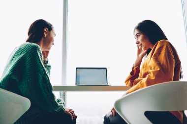 Aşağıda görünümü iki yetenekli öğrencilerin boş ekran alanı için reklam ile modern netbook oturan samimi konuşmayı. Kadın tasarımcılar birbirleri ile yaratıcı fikirler hakkında iletişim