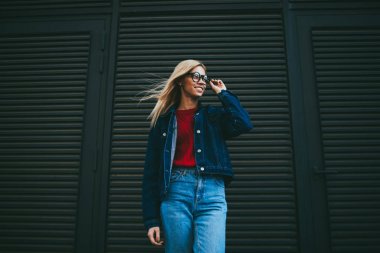 Optik Gözlük reklam metin mesajınız için promosyon siyah arka plan üzerine poz muhteşem sarışın genç kadın. Şık neşeli hippi kız Kot ceket uzağa bakarak giyinmiş