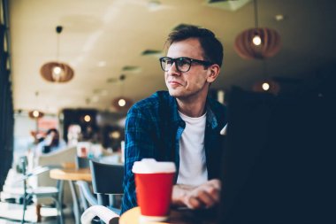 Genç pozitif düşünceli akıllı freelancer özellikleri müşteri projesi için geliştirirken durulması gözlük içinde. Kişisel Web sitesi için yaratıcı fikirler düşünmeye yakışıklı mutlu erkek blogger