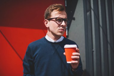 Kendine güvenen erkek kişi şık gözlük rekreasyon take away içecek ile güneşli kentsel ayarında zevk içinde yakışıklı genç. Yakışıklı yaz sokak boş zaman zaman içki ile harcama