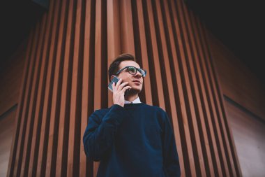 İyi görünümlü kendine güvenen erkek öğrenci yaz ayarlama ve telefonda konuşurken kentsel adlı yürüyüş şık elbise giymiş. Yakışıklı hipster adam ile sokulgan yolu ile modern cep telefonu açık havada iletişim