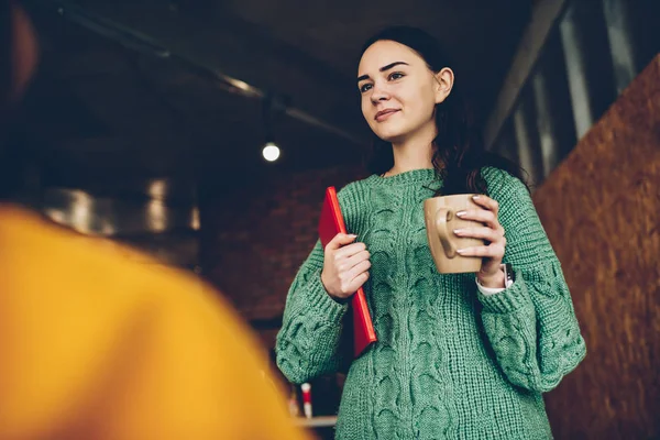Büyüleyici kadın Müdürü lezzetli içecek ve eller klasöründe holding esmer saçlı. Yaratıcı tasarımcı giyim ayakta çay bir fincan ile oda ofis giyinmiş