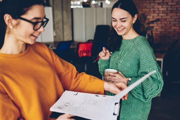 Neşeli yetenekli öğrenciler Bina planları izlerken sırasında gülüyor. Pozitif iki tasarımcıları birlikte Office ortak görev üzerinde çalışmaya. Gülümseyen yaratıcı kadın Mimarlar skeçler iç kontrol