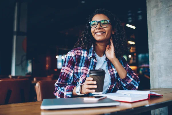 梦幻般的微笑非洲裔美国学生在拿着可口的咖啡在休息的时候 在书本上思考书籍的情节 正面深色皮肤的青少年卷曲的头发思考创造性的想法 — 图库照片