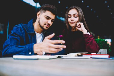 Düşünceli erkek ve kadın öğrencilerin sosyal ağ smartphone aygıt üzerinde içerik izlerken genç hippi çift kafede otururken cep telefonu üzerinden internet Webinar video izleme sahip