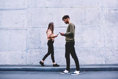Erkek ve dişi hipsters birbirimizi görmezden gri duvar arka plan üzerinde yürüme tercih sosyal ağlar, sohbet online pon tanıtım alanı geziniyor gerçek hayatta iletişim yerine öğrenciler