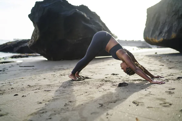 美国黑人年轻女子穿着积极的穿着做瑜伽 Exerciseses 为健康的生命力在热带岛屿的海滨 在清晨的海岸线训练之前 黑皮肤的运动女孩热身 — 图库照片