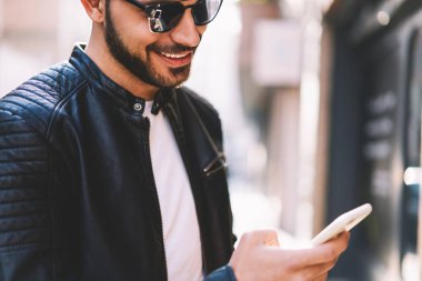 Smartphone Web sitesinde, neşeli adam açık havada ağ üzerinden cep telefonu üzerinde çoklu ortam İndiriyor Internet bağlantısı olan memnun kırpılmış görüntü bilgileri okuma neşeli yakışıklı biri göz