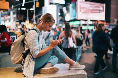 Dönüm noktası, gece, kadın seyahat blogging yeni Yor cep telefonu ve internet bağlantısı gezi yolu ile sosyal ağlar üzerinden fotoğraf göndererek smartphone ile Times Meydanı'nda oturan hippi kız